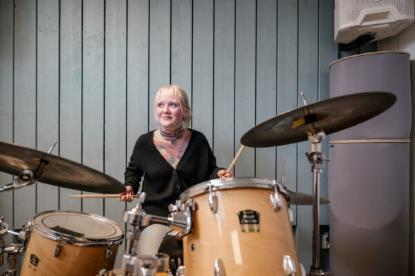 Tjej spelar trummur i studio på skolan.