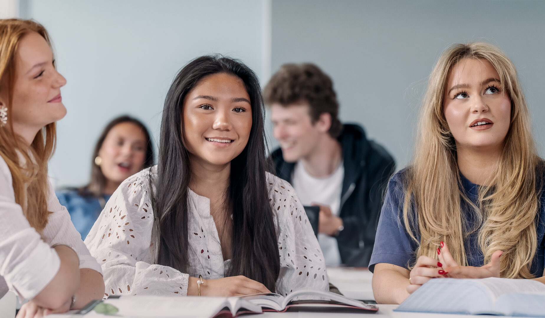Elev sitter i klassrumet under en lektion och ler in i kameran.
