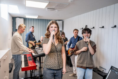 Musikelever sjunger och spelar i studion.