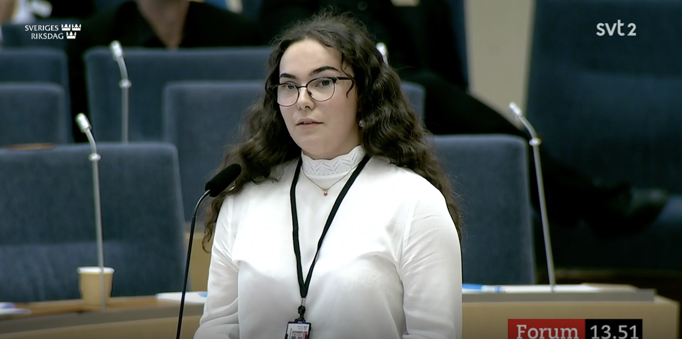 Elev talar vid talarstolen i Sveriges riksdag under en debatt.