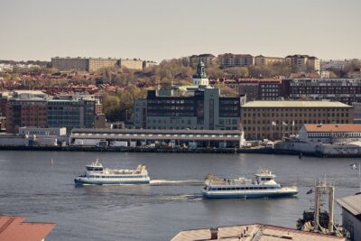 Stadsvy över hamn med färjor och byggnader vid vattnet