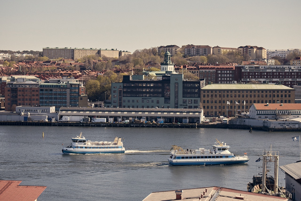 Stadsvy över hamn med färjor och byggnader vid vattnet