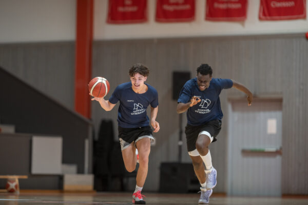 Två killar spelar basket mot varandra.