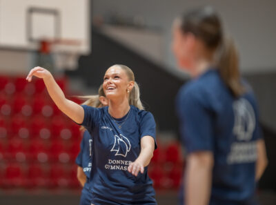 En basketspelare ler när hon slängt iväg sitt kast.