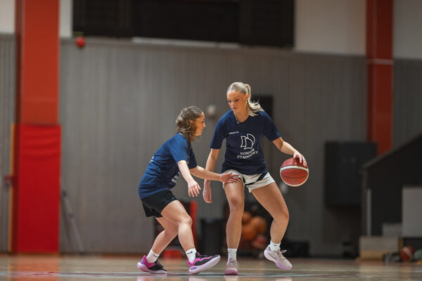 Två tjejer spelar basket mot varandra.